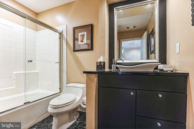 full bath with toilet, vanity, and shower / bath combination with glass door