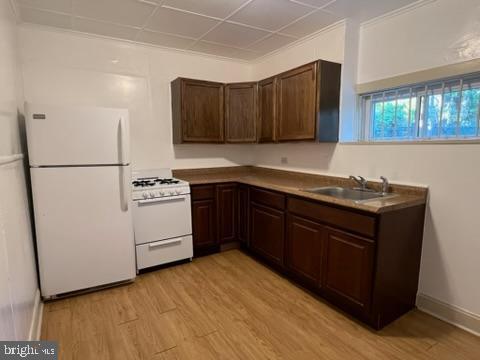 4714 Woodland Ave, Philadelphia, PA 19143 - kitchen with white appliances, a sink, light wood-style flooring, and dark brown cabinetry