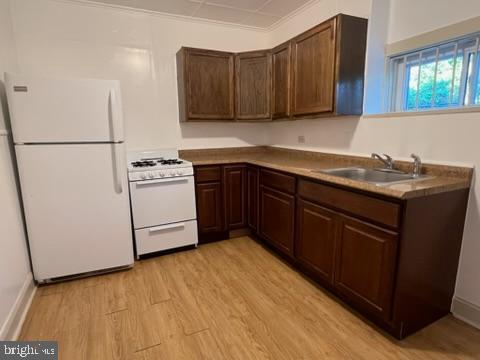 4714 Woodland Ave, Philadelphia, PA 19143 - kitchen with white appliances, a sink, light wood finished floors, and dark brown cabinets