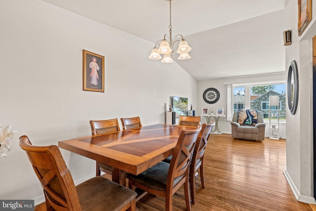 dining area featuring a chandelier, wood finished floors, vaulted ceiling, and baseboards