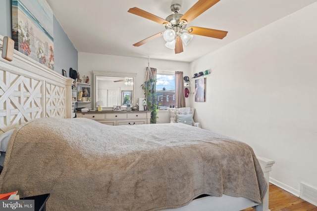 bedroom with wood finished floors, baseboards, and a ceiling fan