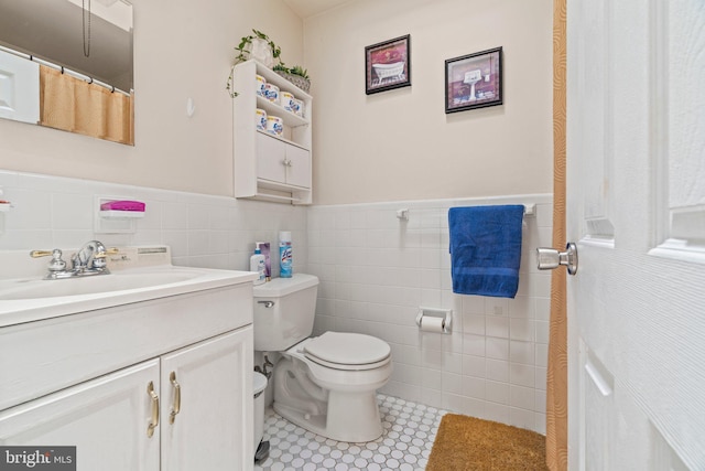 bathroom featuring tile walls, toilet, vanity, wainscoting, and tile patterned floors