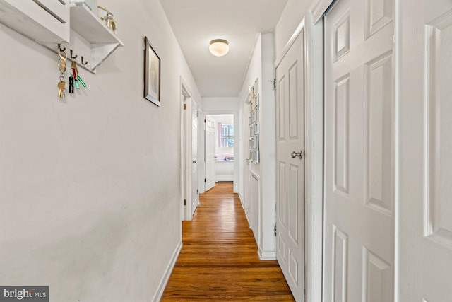 hallway featuring wood finished floors and baseboards