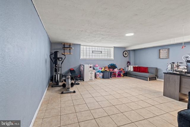 workout area with a textured wall, a textured ceiling, baseboards, and tile patterned flooring
