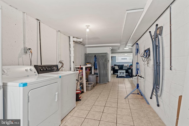 clothes washing area featuring washer and dryer and light tile patterned floors