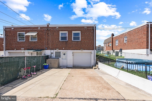 rear view of house with concrete driveway, fence, and an attached garage