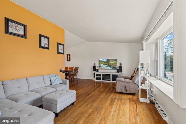 living area featuring hardwood / wood-style flooring, baseboard heating, lofted ceiling, and baseboards