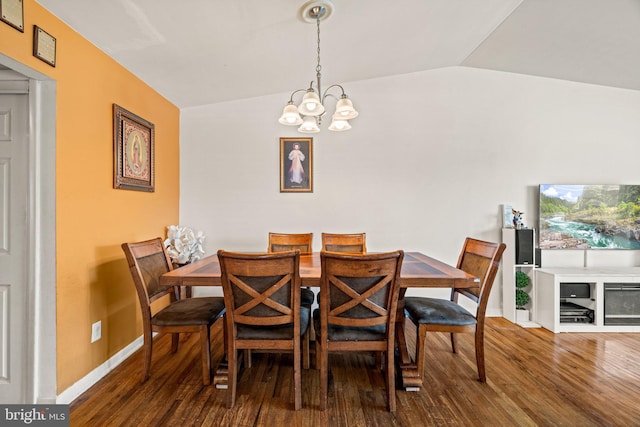 dining space featuring a chandelier, wood finished floors, vaulted ceiling, and baseboards