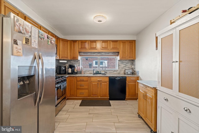 kitchen featuring stainless steel appliances, a sink, tasteful backsplash, and brown cabinets