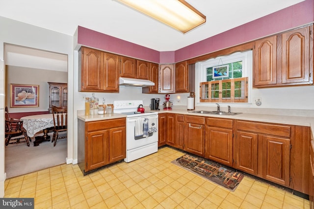 kitchen featuring white electric range oven, under cabinet range hood, a sink, and light countertops
