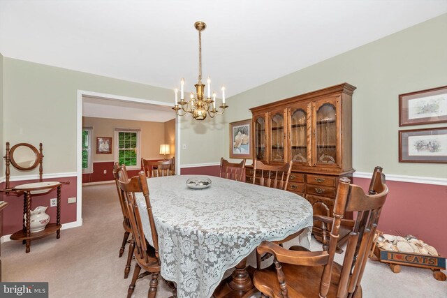 dining room with a chandelier, light carpet, and baseboards