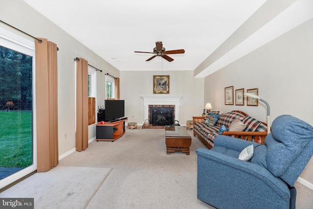 carpeted living room featuring a ceiling fan, baseboards, and a brick fireplace