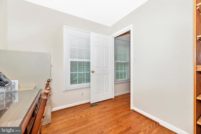 home office with light wood-style flooring, baseboards, and plenty of natural light