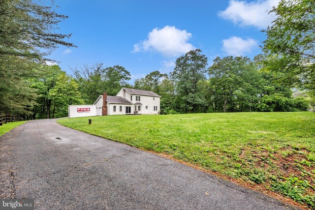 view of front of house with a chimney, a front lawn, and driveway