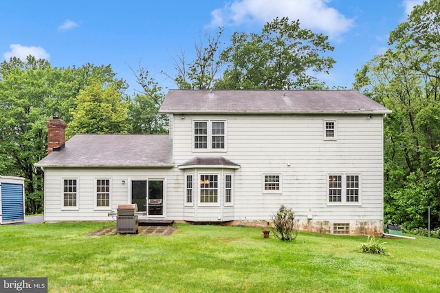 rear view of property with a yard and a chimney