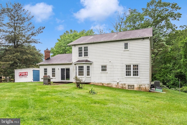 back of house with a chimney, a lawn, central AC, and a shingled roof
