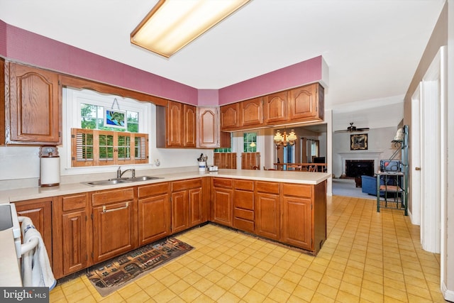 kitchen featuring a fireplace, light countertops, a sink, and brown cabinetry