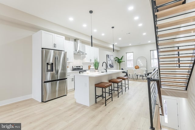 3233 Mercer St, Philadelphia, PA 19134 - kitchen featuring appliances with stainless steel finishes, wall chimney exhaust hood, a breakfast bar area, an island with sink, and light wood finished floors