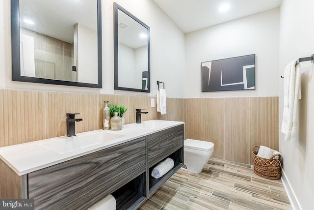 3233 Mercer St, Philadelphia, PA 19134 - bathroom featuring toilet, wainscoting, wood finished floors, double vanity, and tile walls