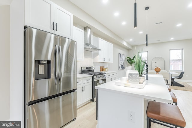 3233 Mercer St, Philadelphia, PA 19134 - kitchen with stainless steel appliances, wall chimney exhaust hood, a center island, a breakfast bar area, and light wood-style flooring