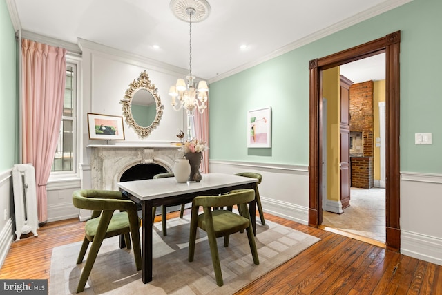 1519 Kingman Pl NW, Washington, DC 20005 - dining space with hardwood / wood-style floors, a premium fireplace, a chandelier, ornamental molding, and a wainscoted wall
