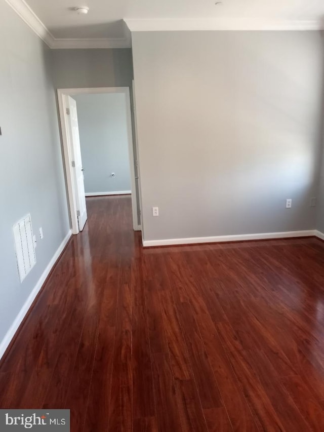 spare room with crown molding, dark wood-style flooring, and baseboards