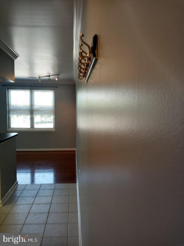 corridor featuring track lighting, light tile patterned flooring, and baseboards