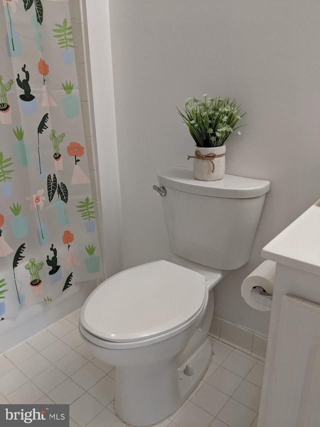 bathroom with toilet, tile patterned floors, a shower with curtain, and baseboards