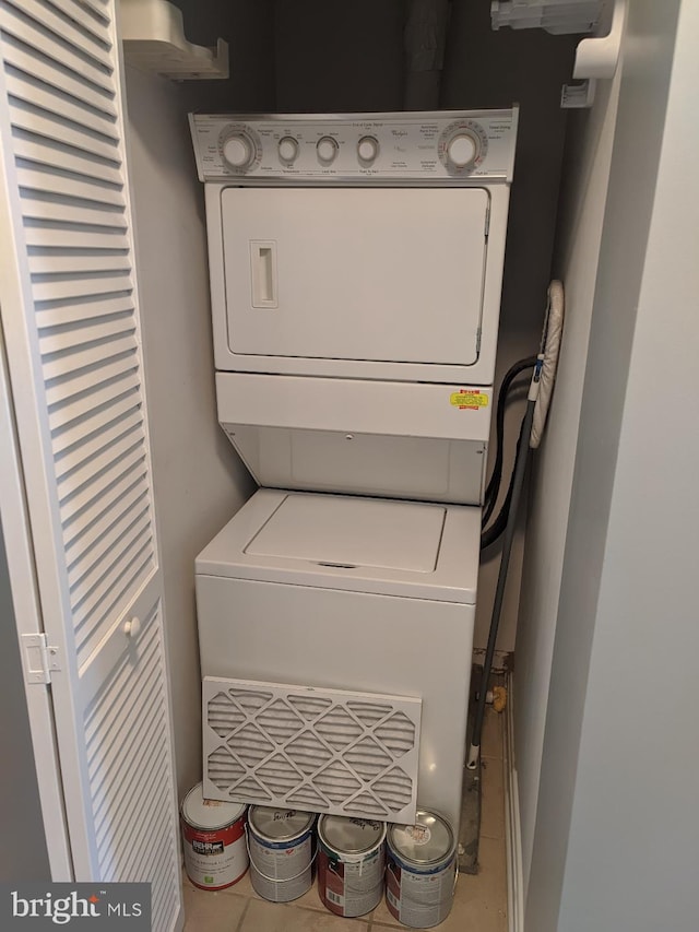 laundry room with stacked washing machine and dryer and tile patterned flooring