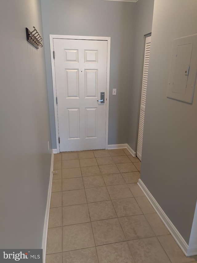 doorway with electric panel, light tile patterned floors, and baseboards