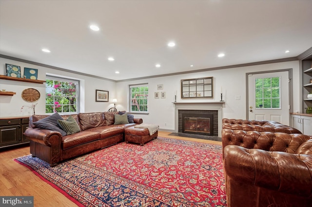 living area featuring crown molding, a brick fireplace, light wood-style floors, recessed lighting, and plenty of natural light
