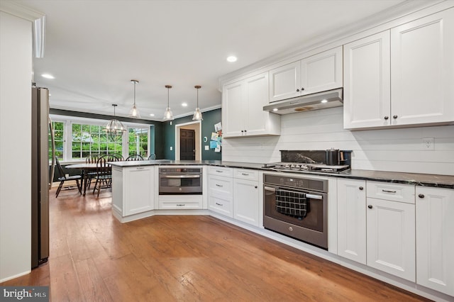 kitchen with stainless steel appliances, under cabinet range hood, white cabinetry, a peninsula, and recessed lighting