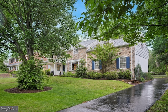 view of front of home with stone siding and asphalt driveway