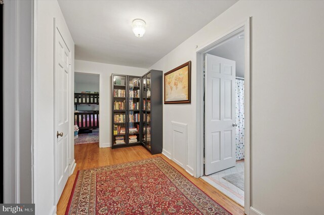 corridor with light wood finished floors and baseboards