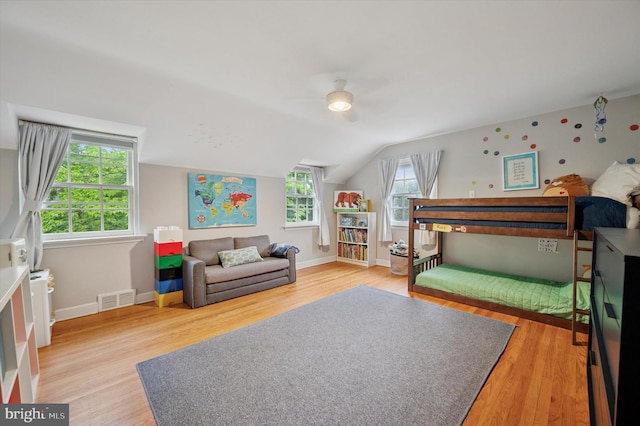 bedroom with light wood-type flooring, lofted ceiling, baseboards, and ceiling fan
