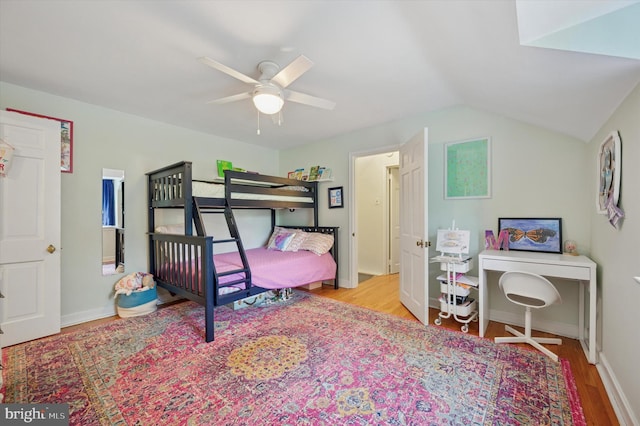 bedroom with wood finished floors, lofted ceiling, baseboards, and ceiling fan