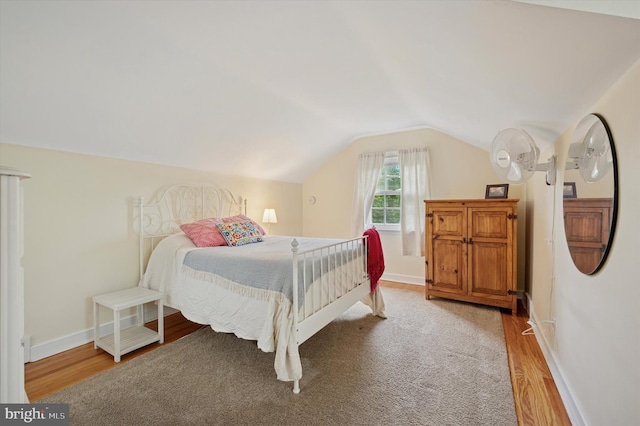 bedroom featuring light wood-style floors, lofted ceiling, and baseboards