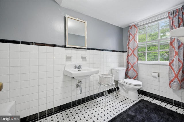 bathroom featuring tile walls, toilet, and a wainscoted wall