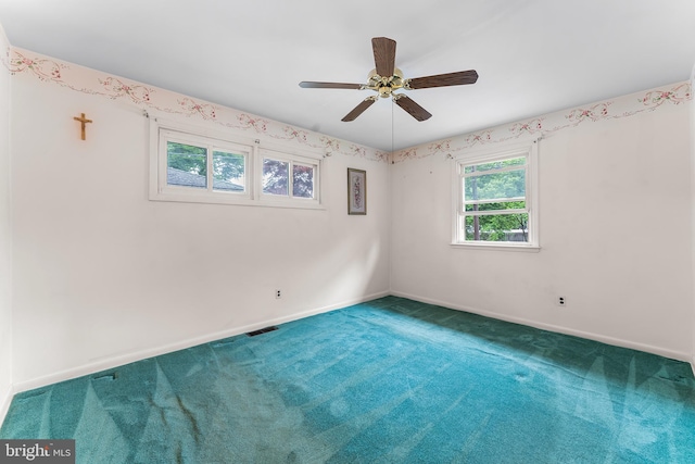 carpeted spare room featuring baseboards and a ceiling fan