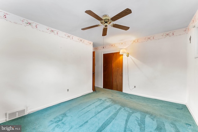 carpeted spare room featuring a ceiling fan and baseboards