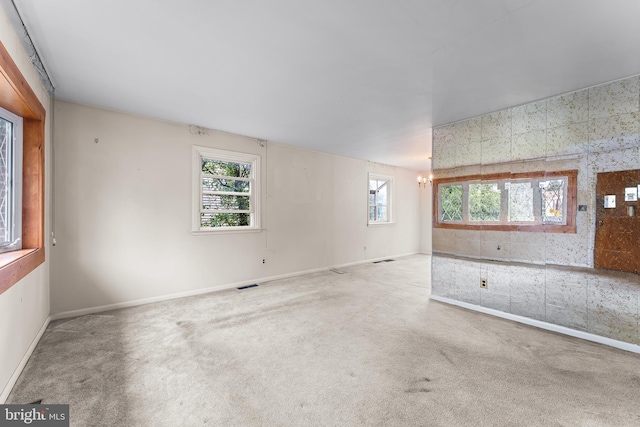 unfurnished room featuring a chandelier, baseboards, and carpet floors