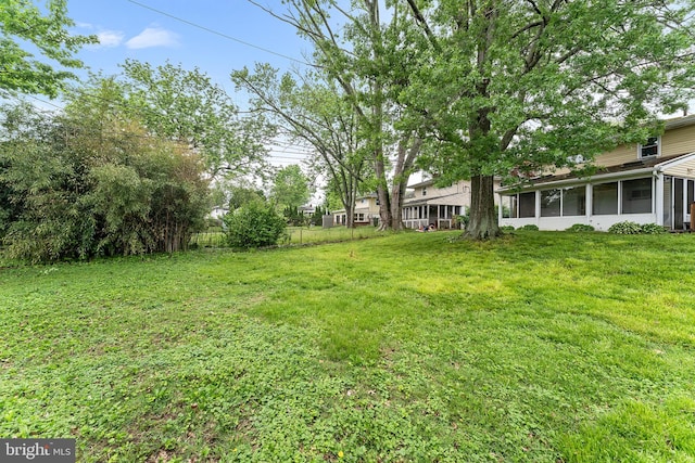 view of grassy yard with a sunroom