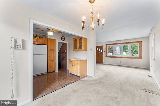 kitchen featuring freestanding refrigerator, baseboards, a chandelier, ceiling fan, and light countertops