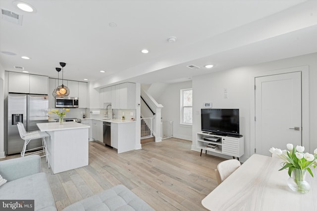 1325 N 17th St Unit A, Philadelphia, PA 19121 - kitchen featuring stainless steel appliances, a kitchen island, light countertops, light wood-style floors, and backsplash