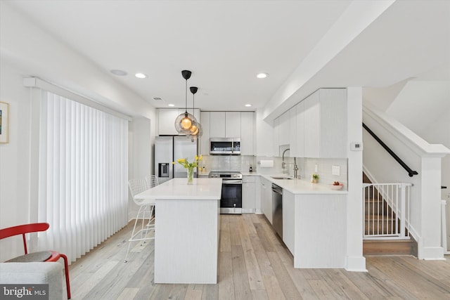 1325 N 17th St Unit A, Philadelphia, PA 19121 - kitchen featuring appliances with stainless steel finishes, a center island, light countertops, a kitchen breakfast bar, and light wood-type flooring