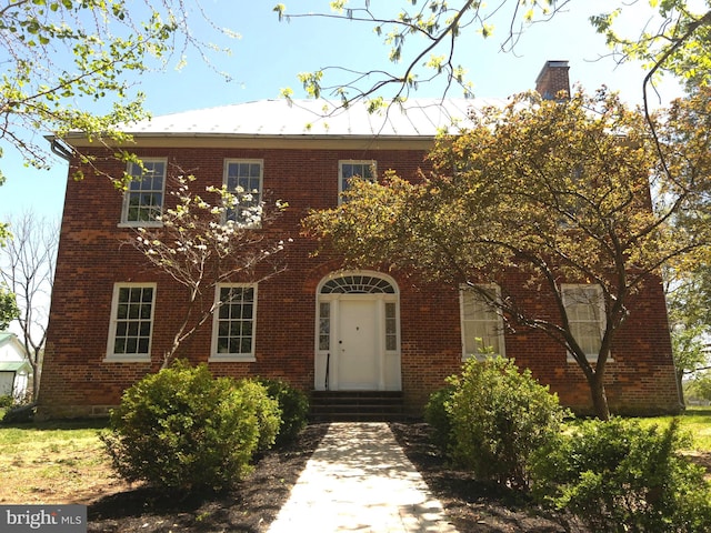 view of front of property with entry steps, a chimney, and brick siding