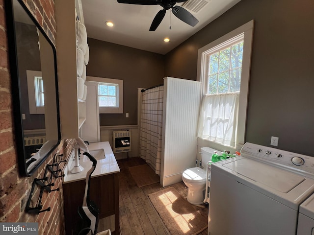 bathroom featuring hardwood / wood-style flooring, washer and dryer, toilet, ceiling fan, and heating unit