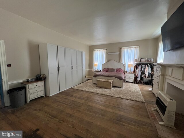 bedroom featuring dark wood-type flooring, heating unit, and a closet