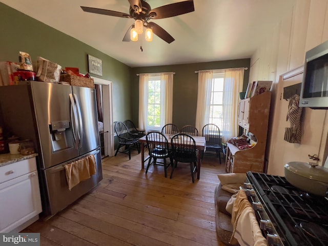 kitchen featuring stainless steel appliances, hardwood / wood-style flooring, ceiling fan, white cabinets, and light stone countertops