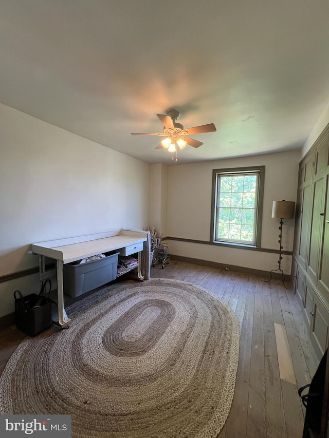 bedroom featuring hardwood / wood-style floors, a ceiling fan, and baseboards